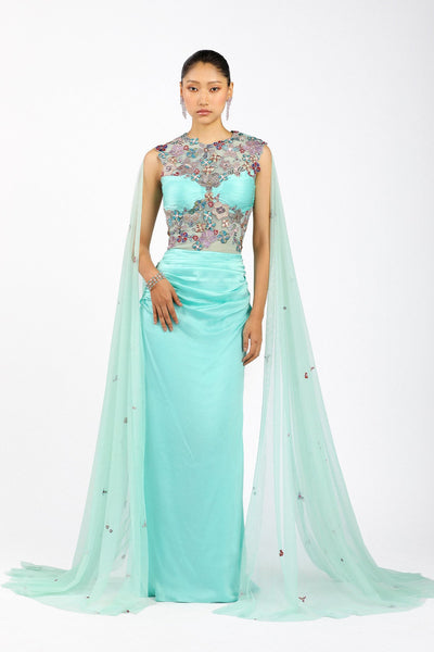 Woman wearing Matilda scuba blue satin ruffled gown with cape