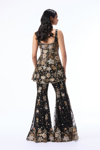 Woman wearing a floral peplum top and bell-bottom pants on a white background