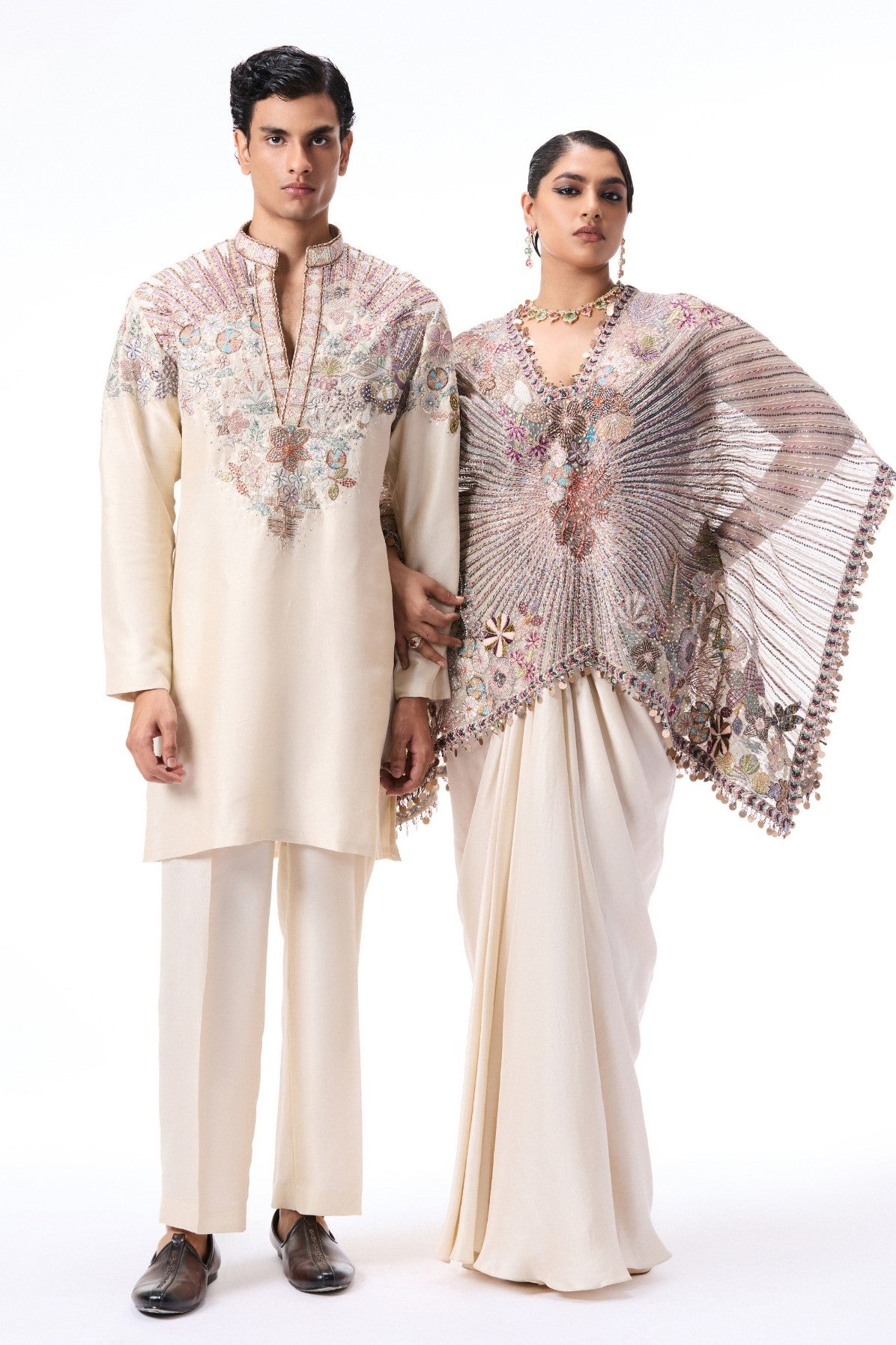 Man and woman in traditional embroidered outfits on a white background