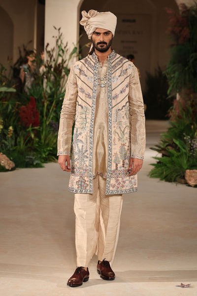 Full look of the light gold raw silk long bundi paired with Banarasi tissue brocade kurta and pants.