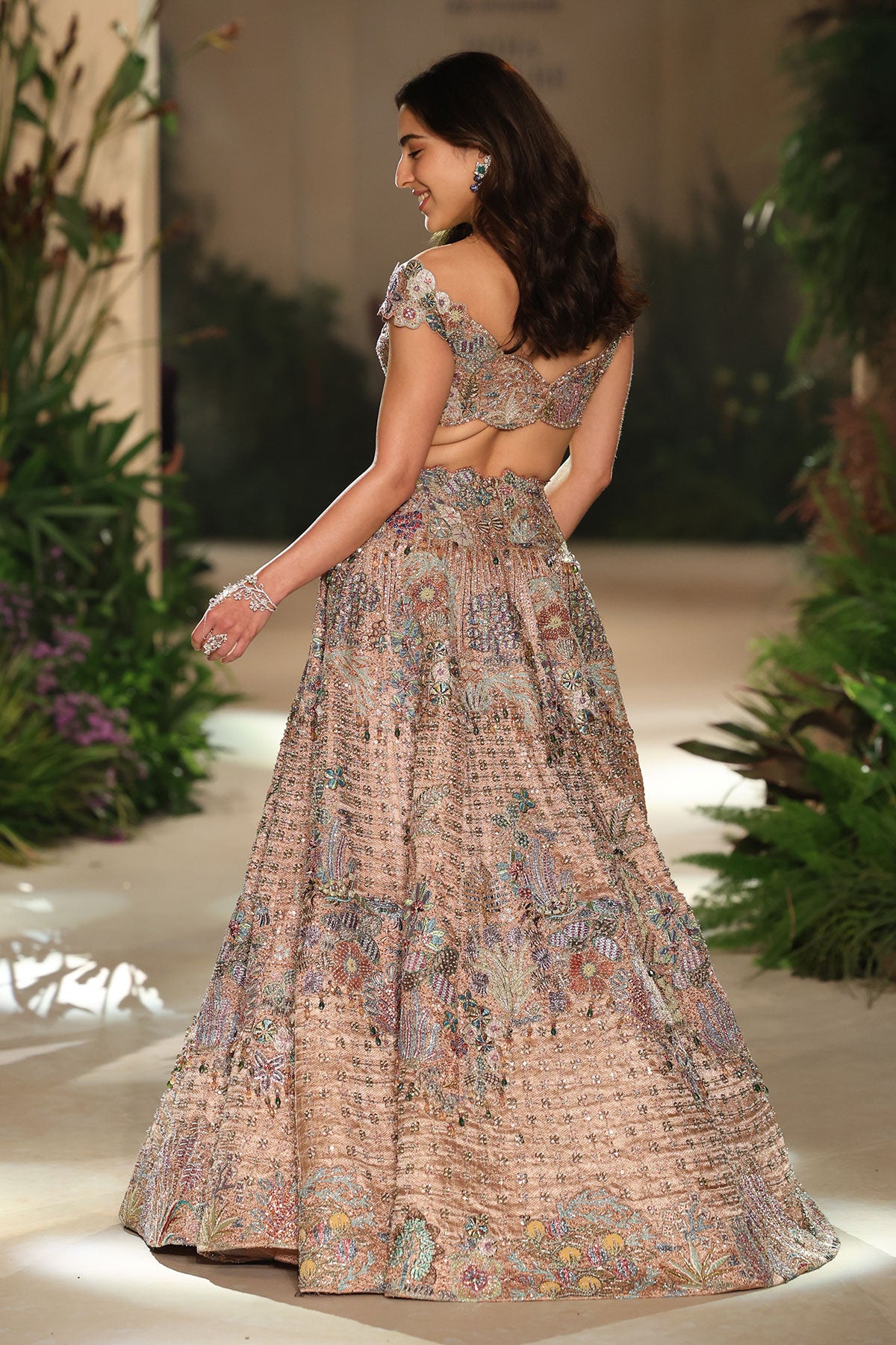 Back profile of the rose gold applique embellished brocade lehenga with halter-strap tassel blouse.
