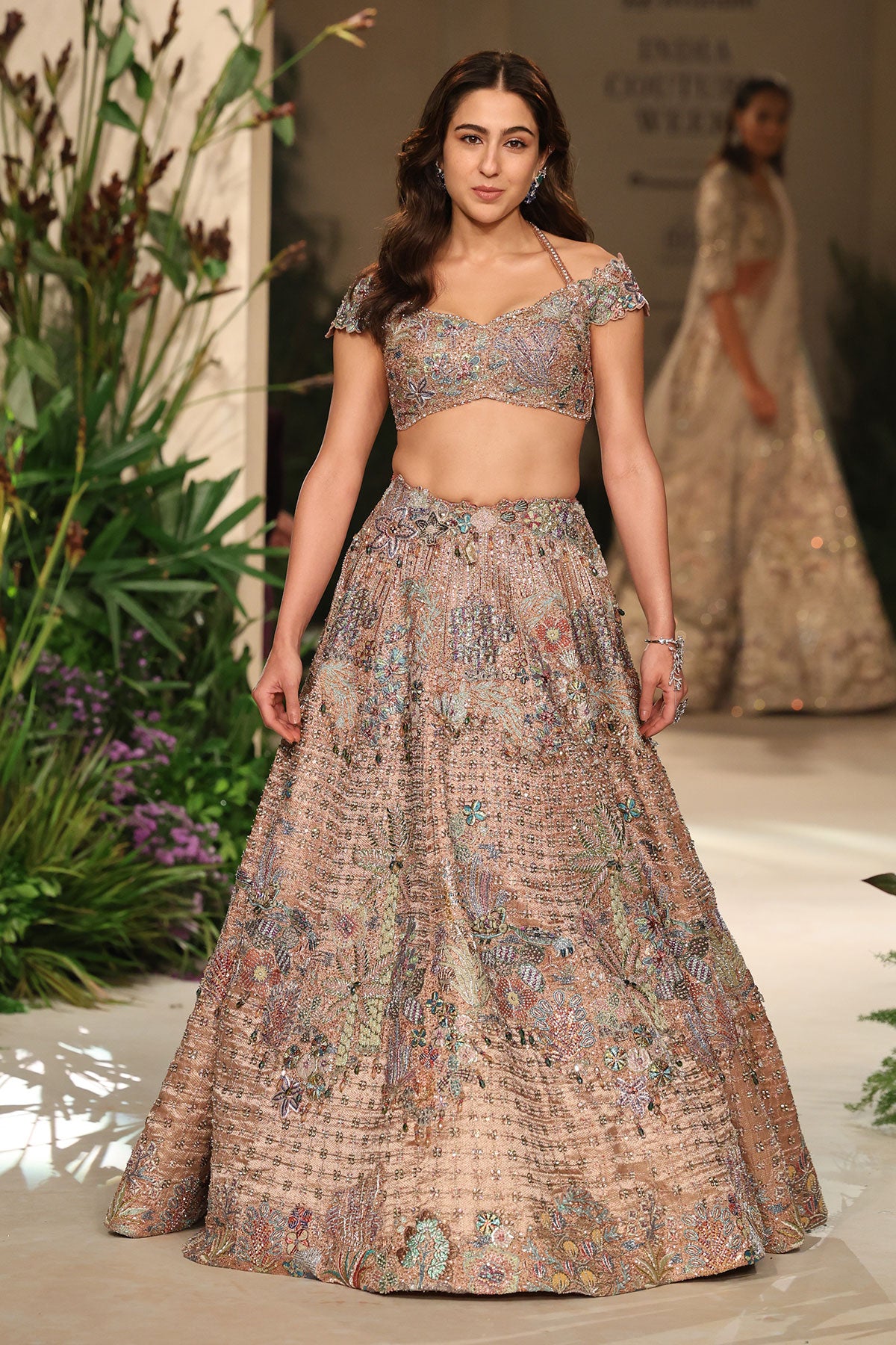 Wild At Heart rose gold Banarasi tissue brocade lehenga shown in a front view with off-shoulder halter-strap tassel blouse and tulle dupatta.