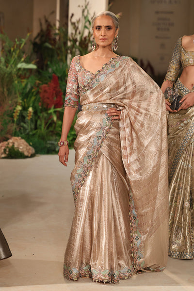 “Champagne pink tissue brocade Banarasi saree with ornate border and soft shimmering texture.”