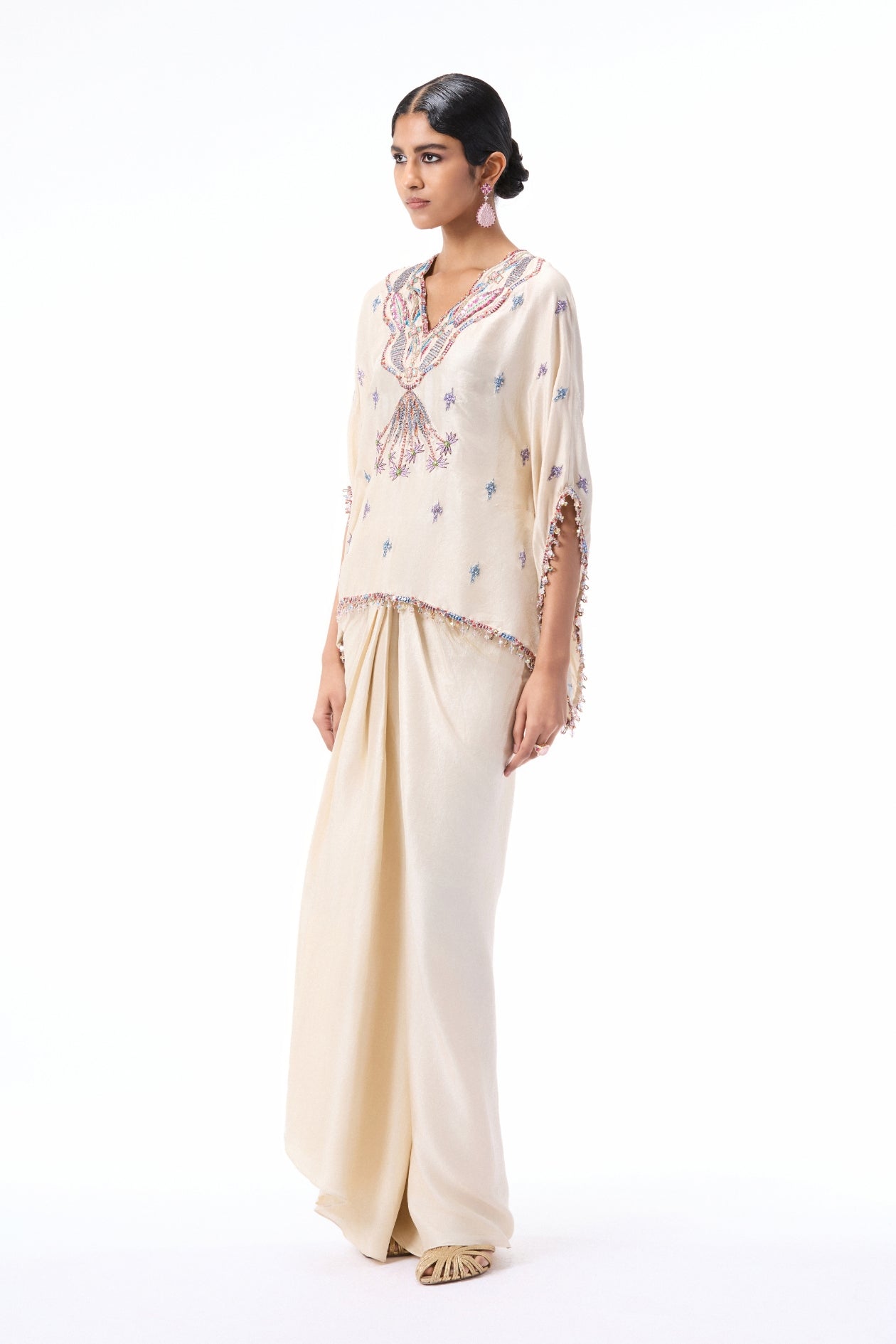 Side angle view of the ivory dupion silk short kurta and pleated draped skirt with applique detailing.