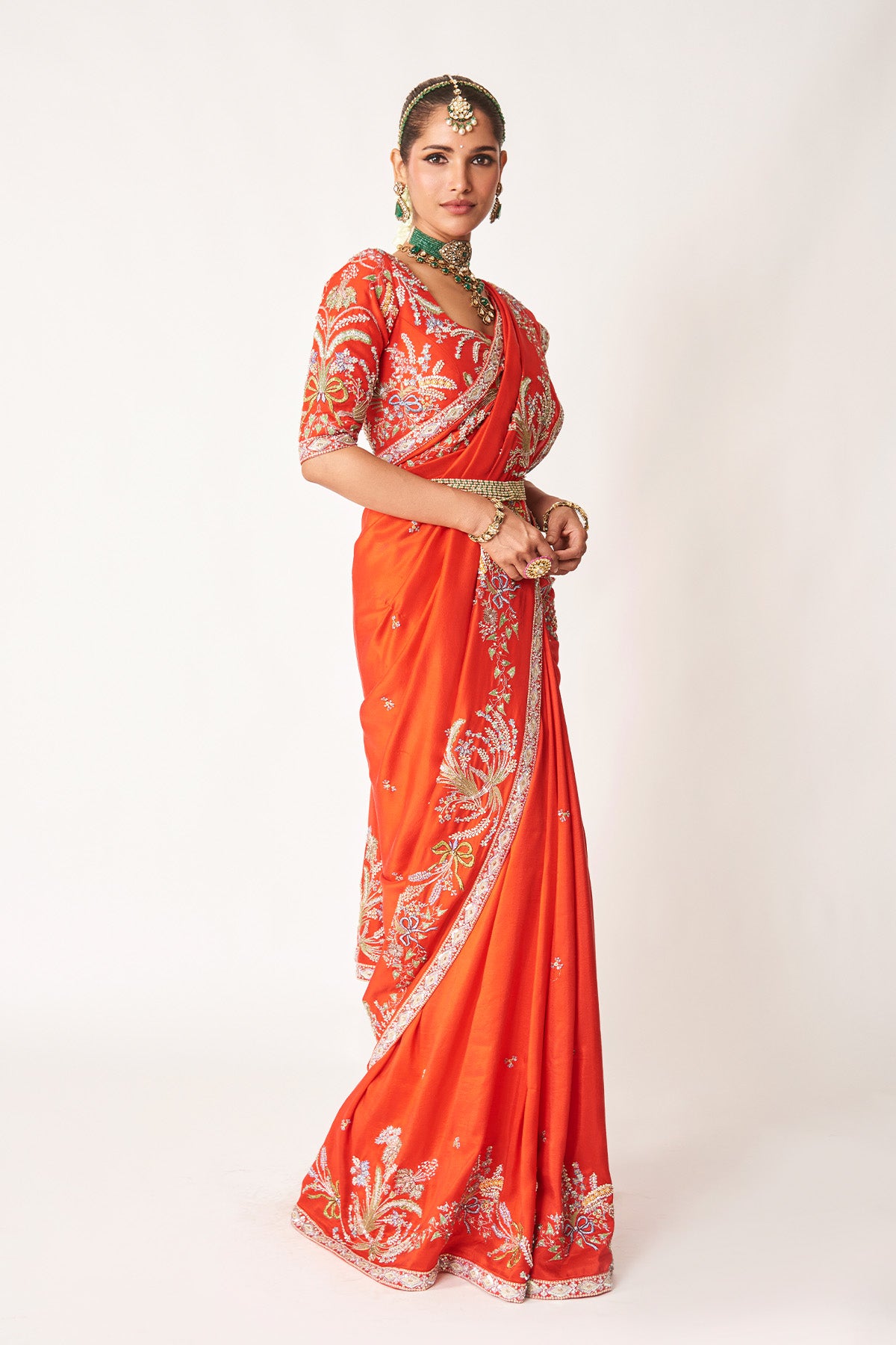 Woman in red embellished saree from right angle