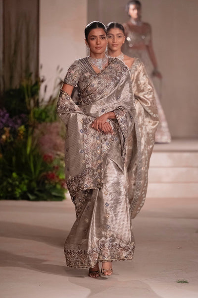 “Motion shot of the silver Banarasi tissue brocade saree highlighting its fluid drape.”