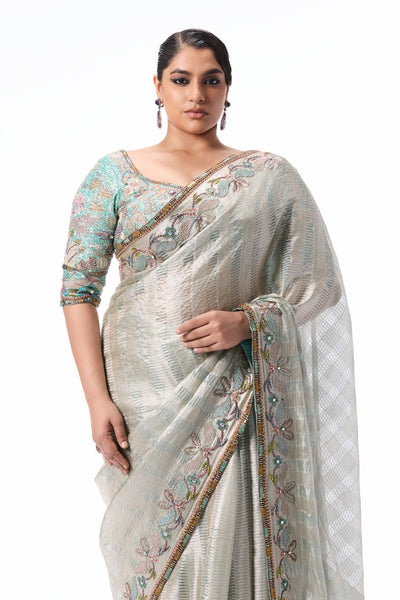 “Silver blue Banarasi tissue brocade saree with silver applique embellished border paired with a blue tissue blouse from the Wild At Heart collection.”