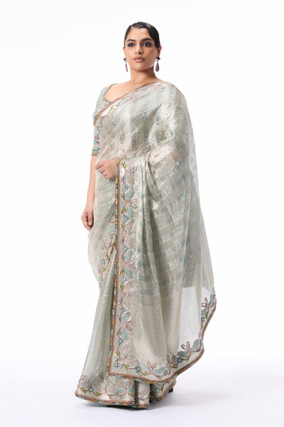 “Silver tissue brocade saree with blue undertones, enriched with silver applique border and blue blouse.”
