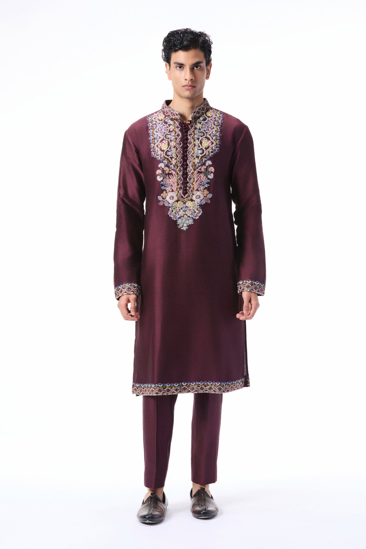Man wearing a maroon embroidered traditional outfit on a white background