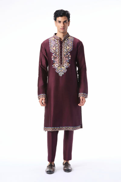 Man wearing a maroon embroidered traditional outfit on a white background