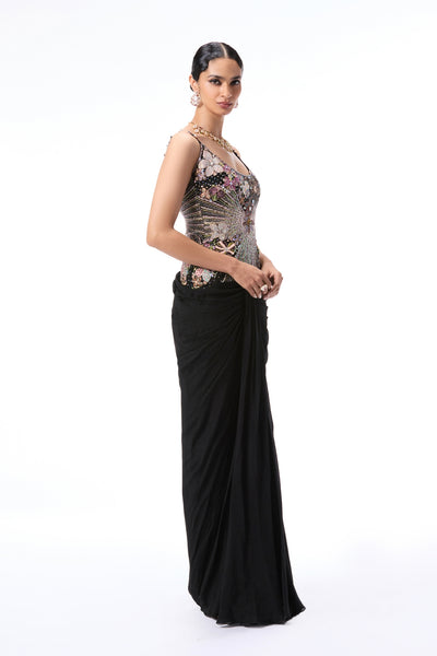 Left side view of woman in black applique embellished tulle and chiffon gown