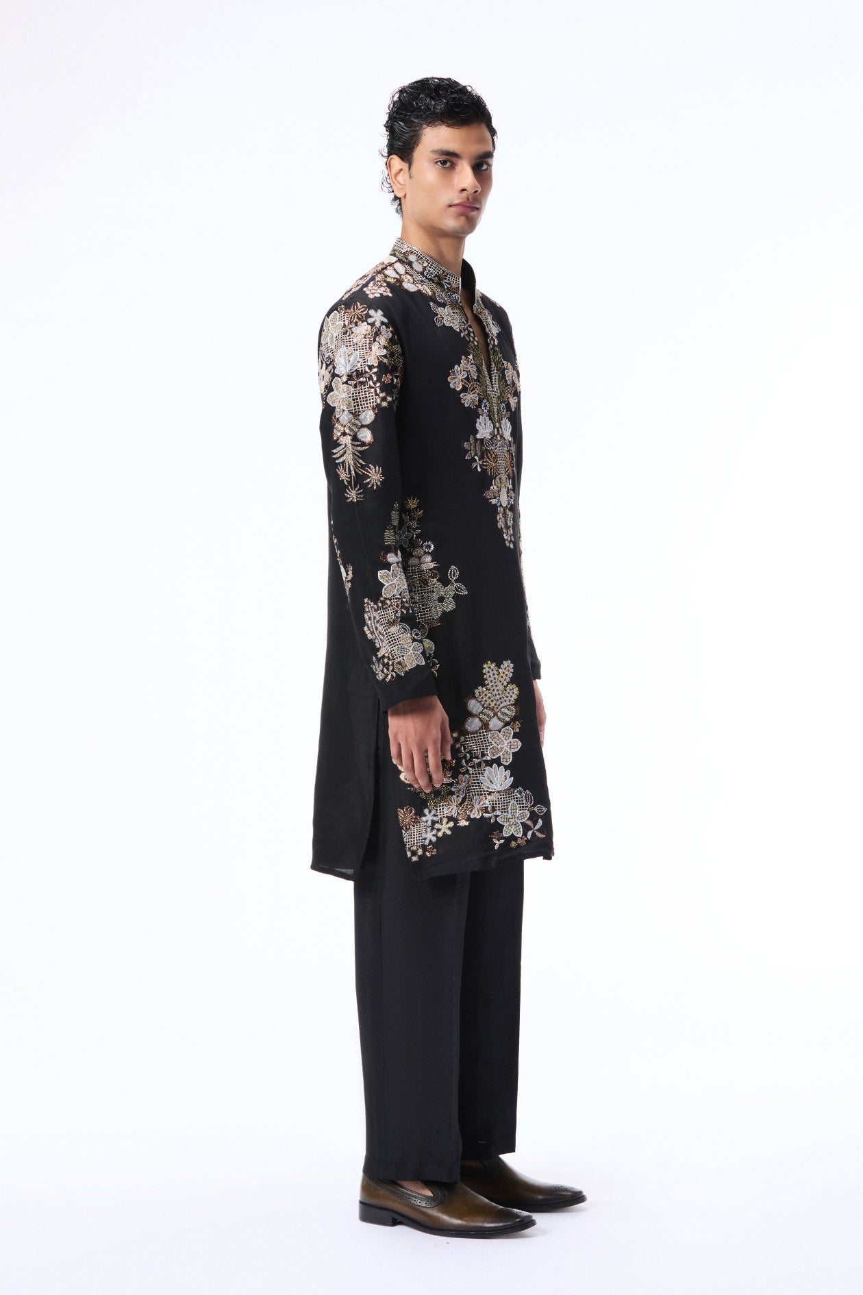 Man wearing a black embroidered sherwani with dark trousers 