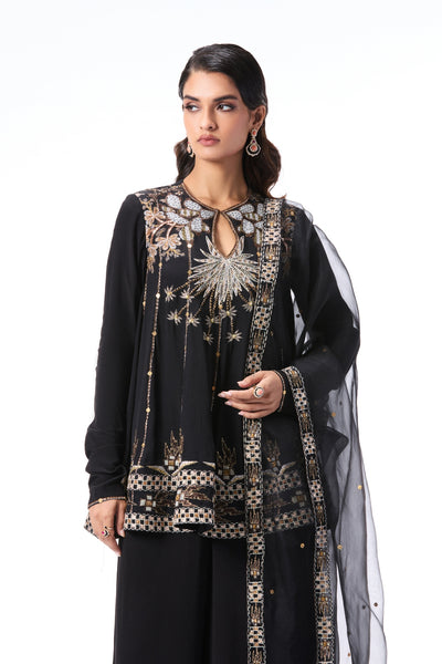 Woman wearing a black and gold embroidered traditional outfit on a white background