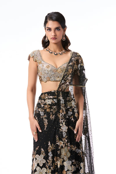 Woman wearing a black floral saree with a silver blouse on a white background