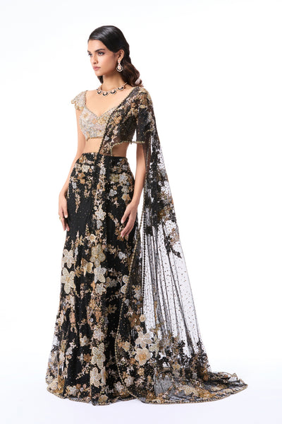 Woman wearing a black floral saree with a white blouse on a white background