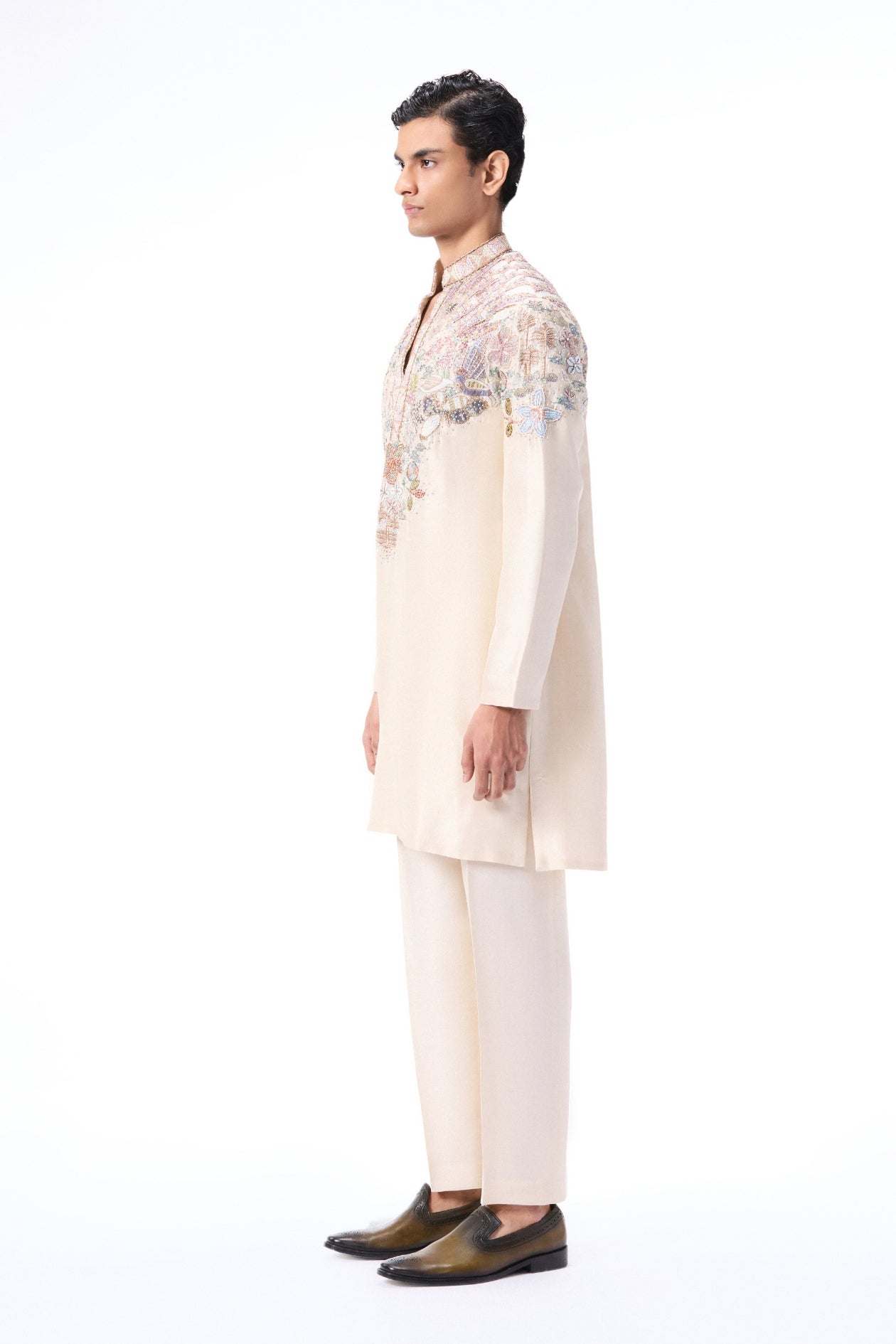 Man wearing a traditional embroidered kurta with white pants o