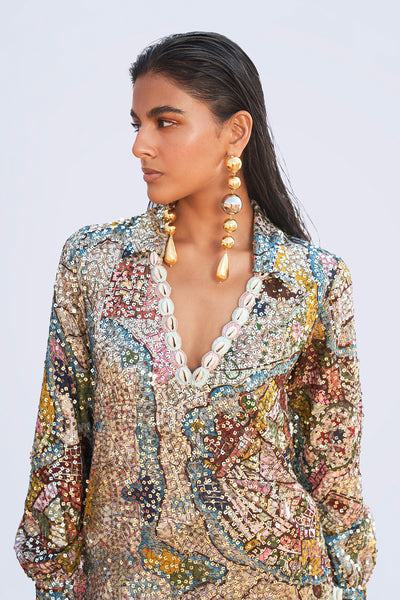 Close detail capturing the sequin appliqué and shimmering ivory texture of the tunic