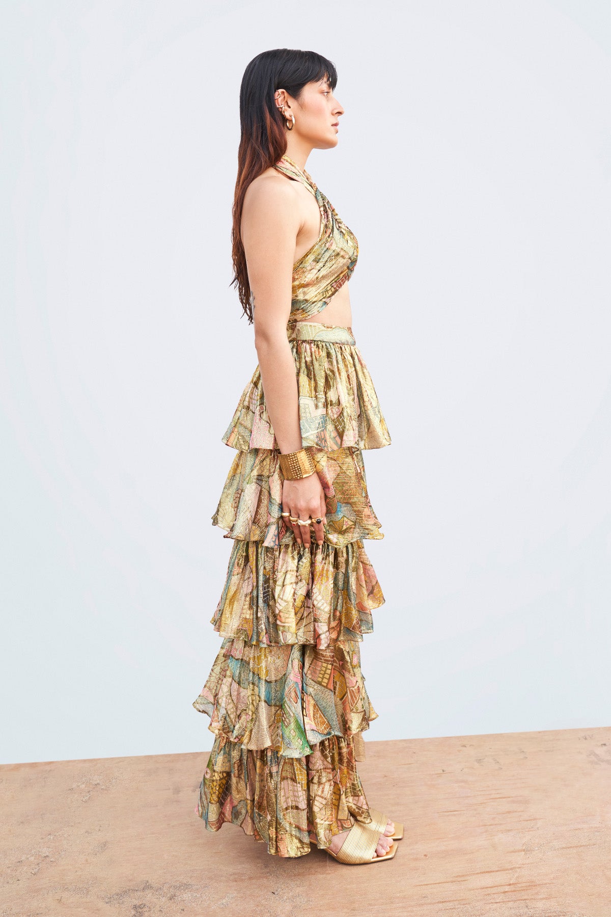 Left profile of gold twisted top and layered midi skirt.
