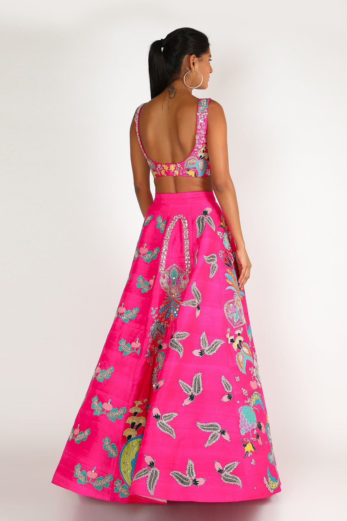 Back view of fuschia pink nadenka raw silk appliquéd lehenga with blouse and cutwork tulle dupatta