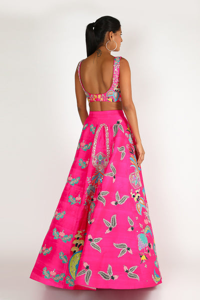 Back view of fuschia pink nadenka raw silk appliquéd lehenga with blouse and cutwork tulle dupatta