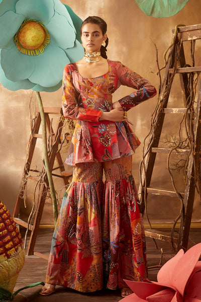 Front view of fiery red pastiche printed and embellished gharara set with cutwork dupatta