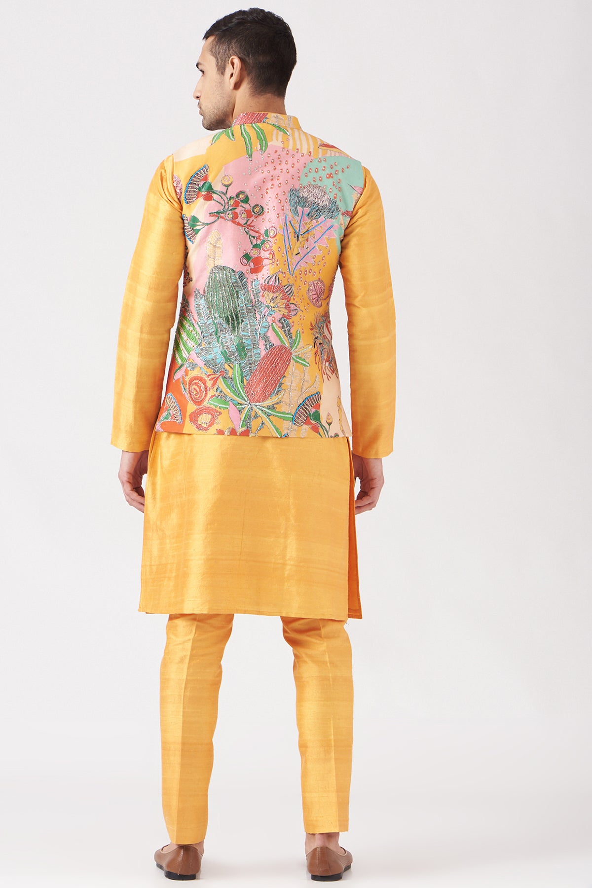 Back view of yellow pastiche raw silk printed and embellished bundi with yellow raw silk kurta and pant